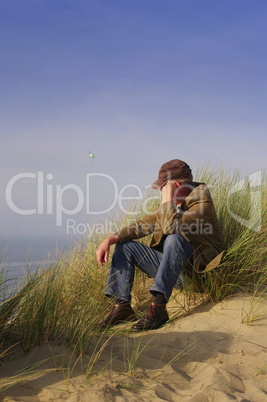 Mann sitzt in der Dünenlandschaft auf Sylt
