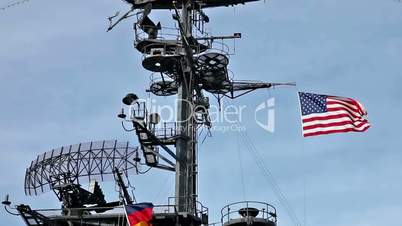 USA flag and antennas on carrier control tower in blue sky