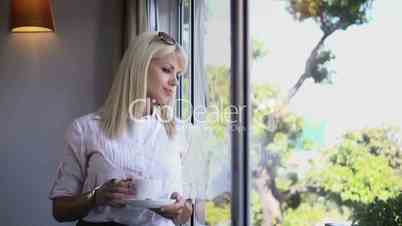 Business woman drinking coffee and staring out of window