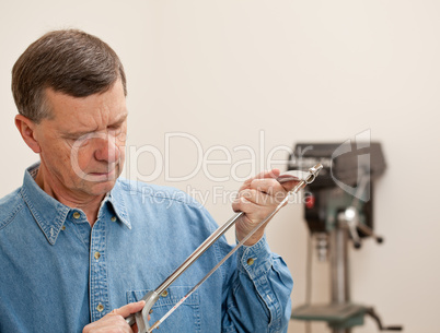 Senior man holding a metal saw