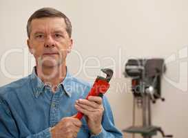 Senior man holding a large wrench