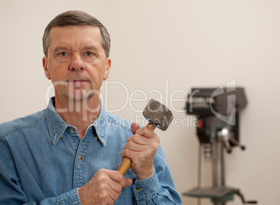 Senior man holding a large hammer