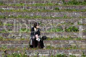 Frau sitzt allein auf Steintreppe