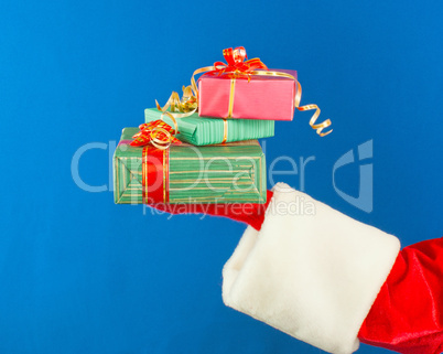 Santa's hand holding presents over blue background