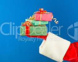 Santa's hand holding presents over blue background