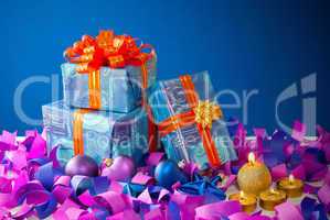 Christmas gifts and candles over blue background