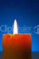 Close up of a burning candle against blue background