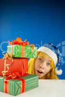 Surprised teen girl looking from behind the Christmas presents