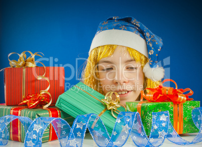 Surprised teen girl looking from behind the Christmas presents