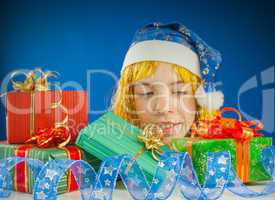 Surprised teen girl looking from behind the Christmas presents