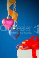 Two heart shaped toys hanging against blue background