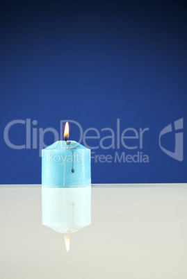 Close up of burning candle against dark blue background