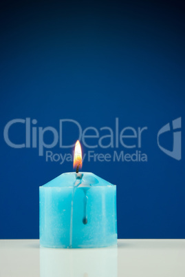 Close up of burning candle against dark blue background