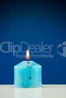 Close up of burning candle against dark blue background