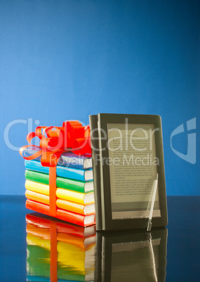 Stack of books with electronic book reader against blue background