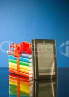 Stack of books with electronic book reader against blue background