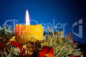 Burning candle with Christmas decorations against blue background