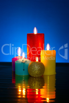 Five burning colourful candles against blue background