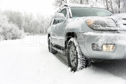 Snowy winter road behind an unrecognizable car