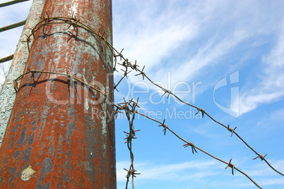 barbed wire on the pole against the blue sky