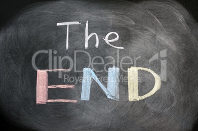 The end - handwritten with chalk on a blackboard with eraser smudges