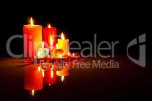 A lot of burning colorful candles against black background
