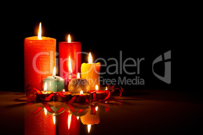 A lot of burning colorful candles against black background