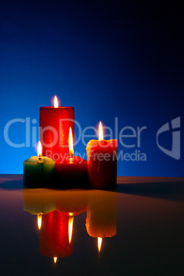 Four burning colorful candles against black background