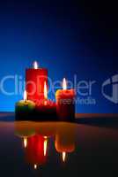 Four burning colorful candles against black background
