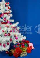 Heap of the Christmas presents under decorated white evergreen t