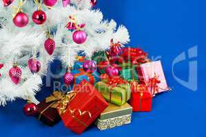 Heap of the Christmas presents under decorated white evergreen t