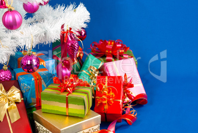 Heap of the Christmas presents under decorated white evergreen t