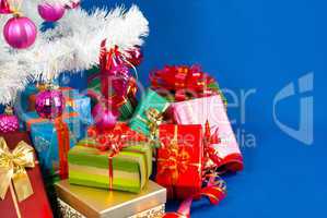 Heap of the Christmas presents under decorated white evergreen t