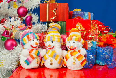Three snowmen in front of the Christmas presents over the blue b