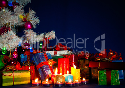 Christmas presents and burning candles against blue background