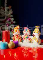Three snowmen and burning candles over the blue background