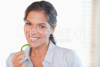 Smiling woman eating a slice of pepper