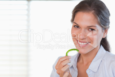 Cheerful woman eating a slice of pepper