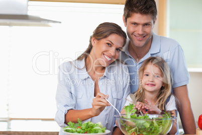 Smiling family preparing a salad