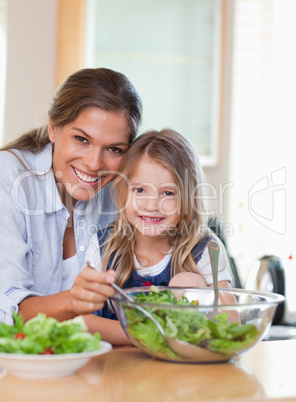 Portrait of a mother and her daughter preparing a salad