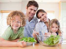 Smiling family preparing a salad together