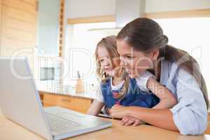 Smiling mother and her daughter using a laptop
