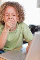 Portrait of a boy yawning while using a laptop