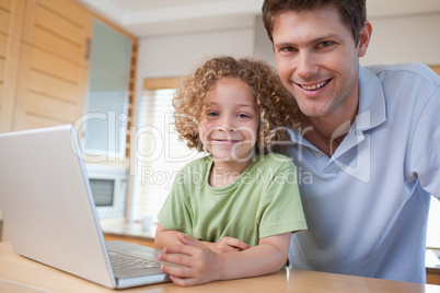 Happy boy and his father using a notebook