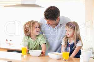 Smiling father with his children having breakfast