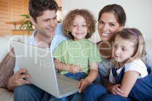 Smiling family using a laptop