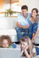 Portrait of cute children using a laptop while their parents are
