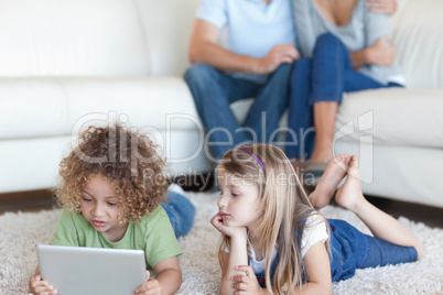 Children using a tablet computer while their parents are watchin