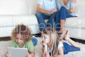 Children using a tablet computer while their parents are watchin