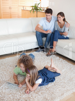 Portrait of children using a tablet computer while their happy p